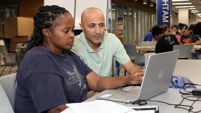 Student and tutor working together using a laptop